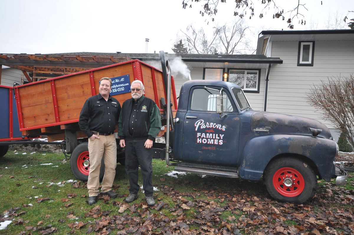 Taylor parsons and gavin parsons stand in front of the Parsons Family Homes old dumptruck with the company logo painted on it