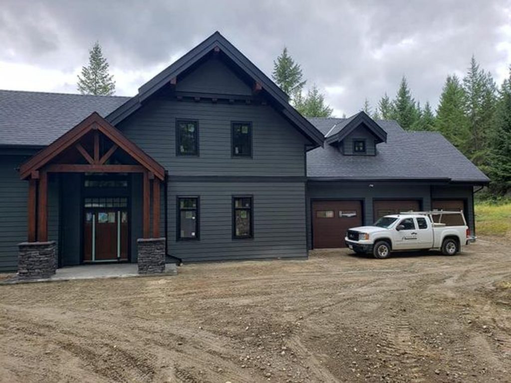 custom home built by parsons family homes showing blue-grey exterior with beam entrance and 3 car garage